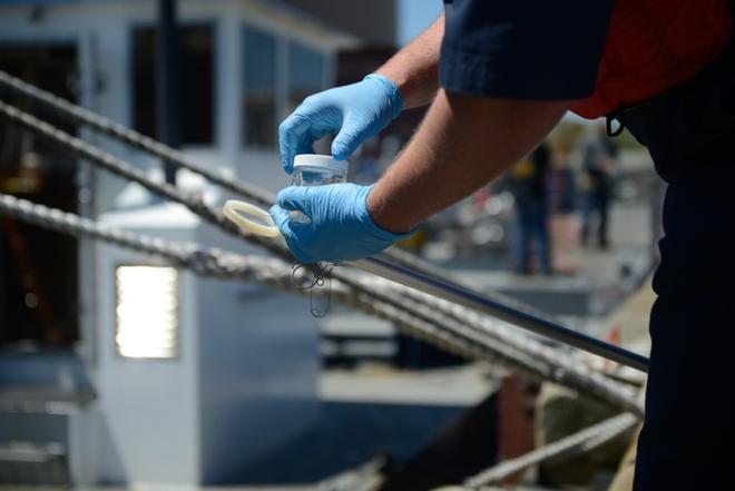 Petty Officer 3rd Class John Northup screws on the lid to a sample jar in New Bedford Harbor, Massachusetts, Tuesday, May 16, 2017. Samples from suspected bilges are documents and taken to the Coast Guard Marine Safety Lab in New London, Connecticut for testing ©  Nicole J. Groll